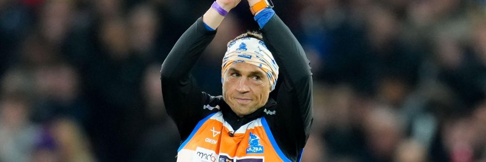 Kevin Sinfeld wearing rugby kit with his hands clapping above his head